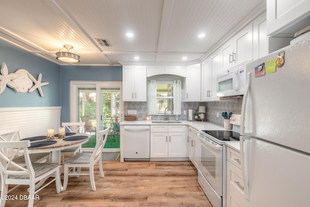 kitchen with light hardwood / wood-style floors, sink, backsplash, white cabinetry, and white appliances