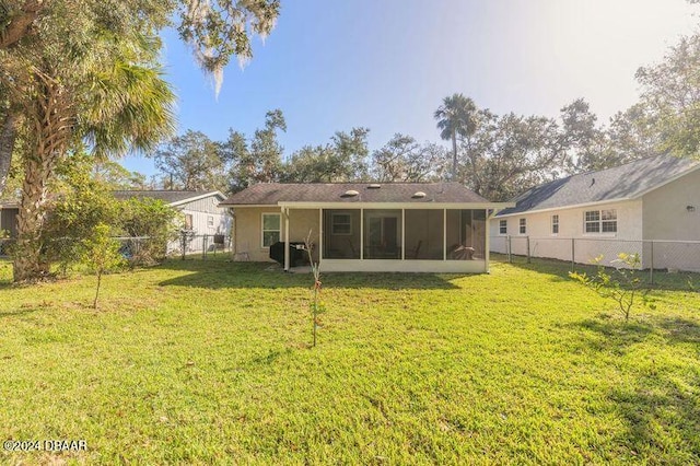 back of property with a sunroom and a lawn