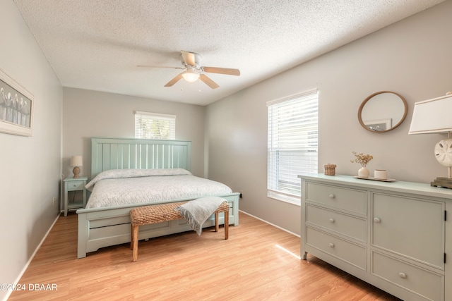 bedroom with ceiling fan, a textured ceiling, and light wood-type flooring