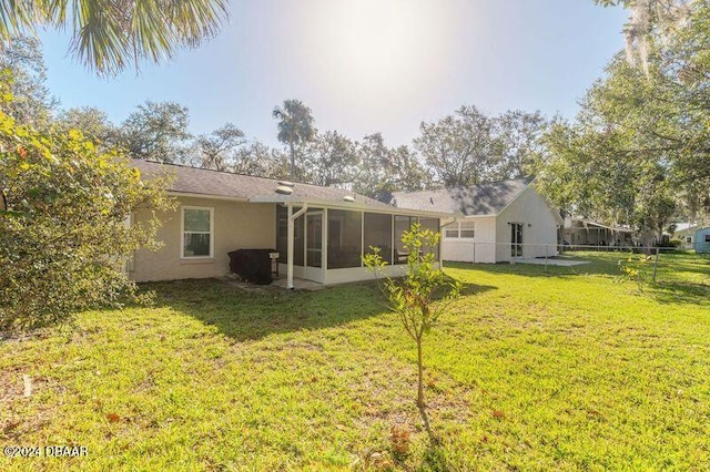 rear view of property with a sunroom and a lawn