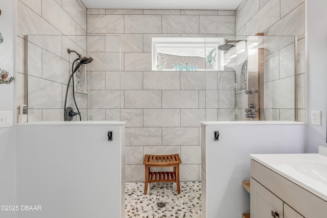 bathroom with tiled shower and vanity