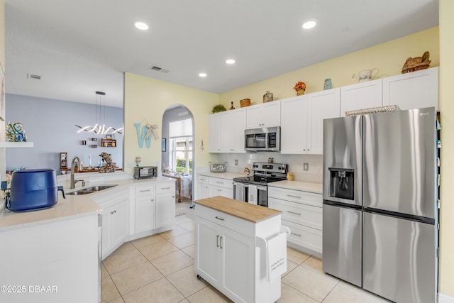 kitchen with white cabinetry, stainless steel appliances, kitchen peninsula, and hanging light fixtures