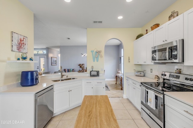 kitchen with sink, white cabinetry, light tile patterned floors, kitchen peninsula, and stainless steel appliances