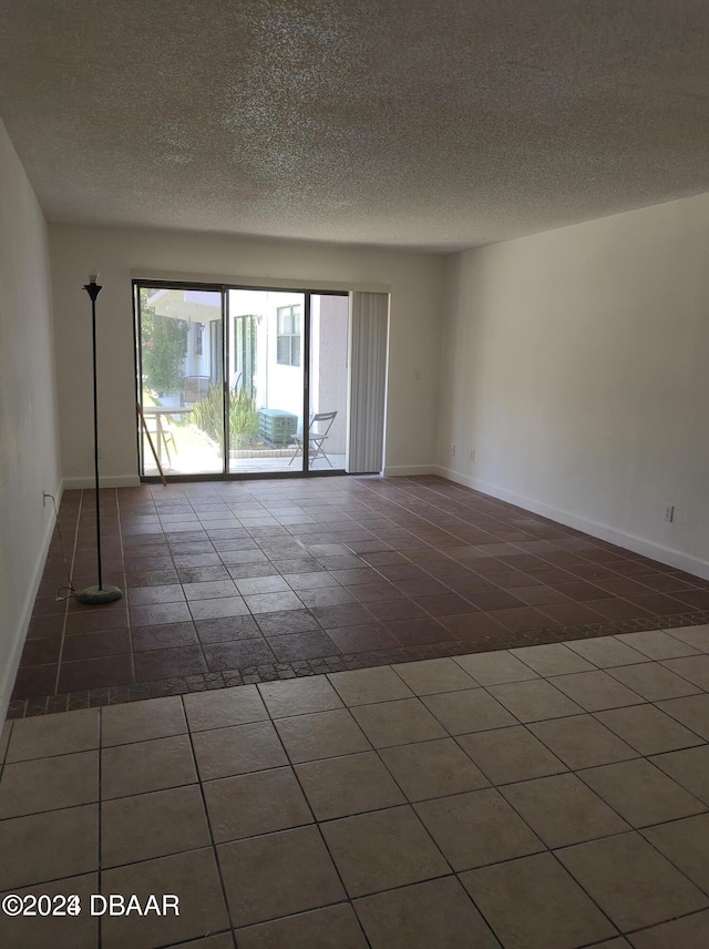 unfurnished room with dark tile patterned flooring and a textured ceiling