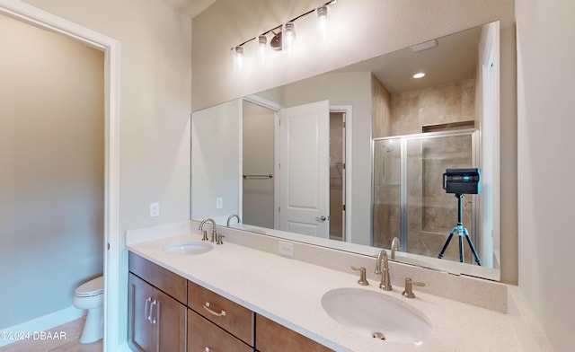 bathroom featuring a shower with shower door, vanity, toilet, and tile patterned floors