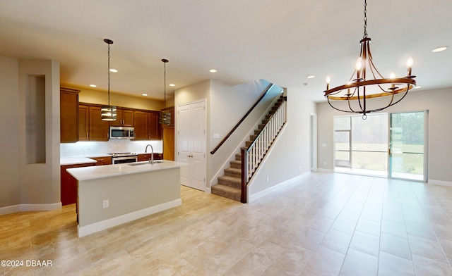 kitchen with stainless steel appliances, hanging light fixtures, sink, an island with sink, and backsplash