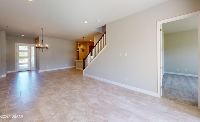 carpeted empty room featuring a chandelier