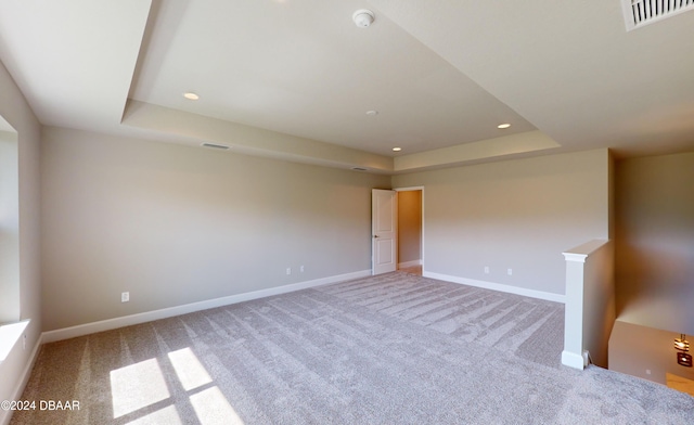 carpeted spare room featuring a raised ceiling