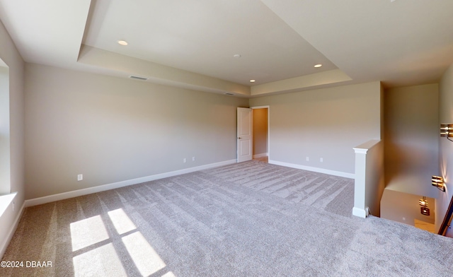 carpeted empty room with a tray ceiling