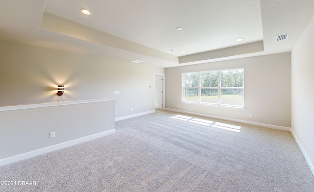 carpeted spare room featuring a tray ceiling