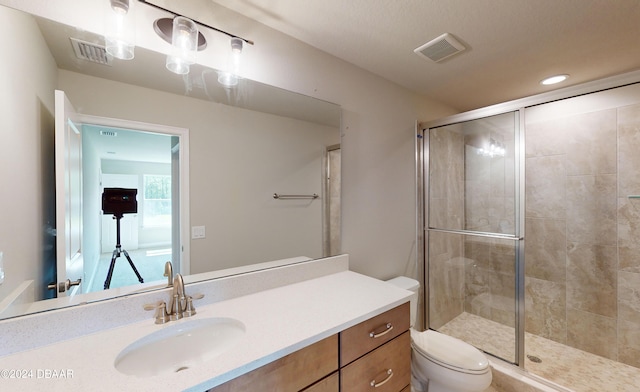 bathroom with an enclosed shower, vanity, and toilet