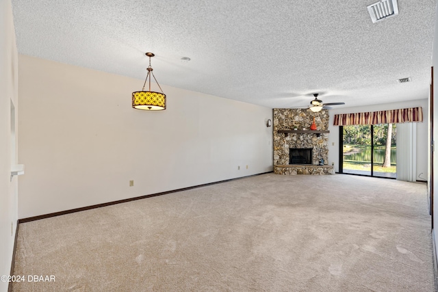 unfurnished living room with light carpet, a textured ceiling, a stone fireplace, and ceiling fan