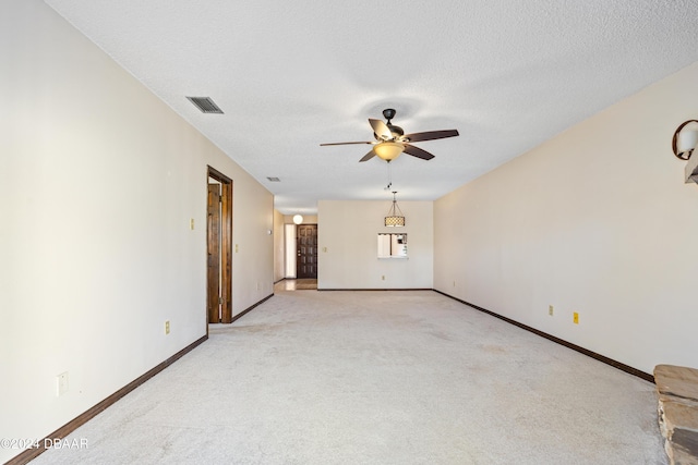 empty room with ceiling fan, light carpet, and a textured ceiling