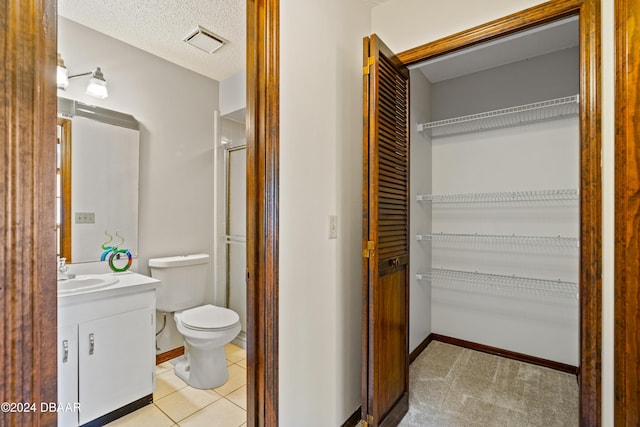 bathroom featuring vanity, tile patterned floors, toilet, a textured ceiling, and a shower with shower door