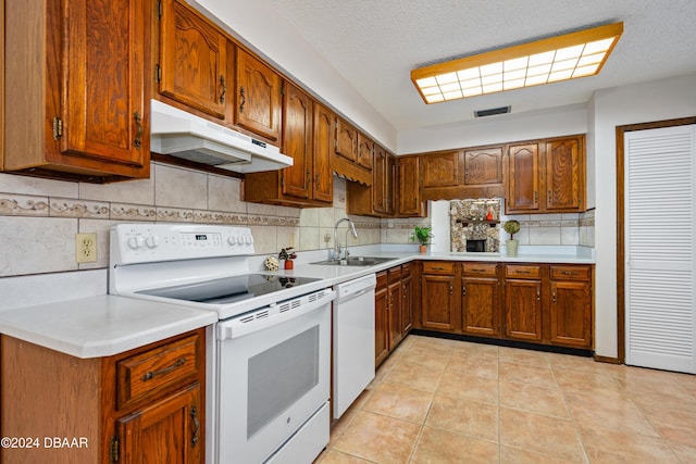 kitchen with a textured ceiling, sink, light tile patterned floors, and white appliances