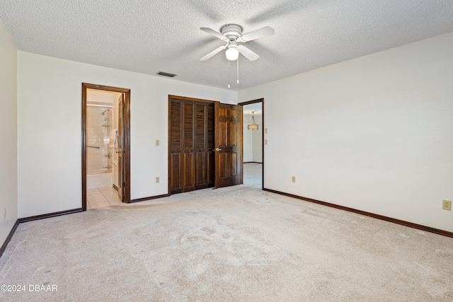 unfurnished bedroom featuring ensuite bathroom, ceiling fan, a textured ceiling, light colored carpet, and a closet