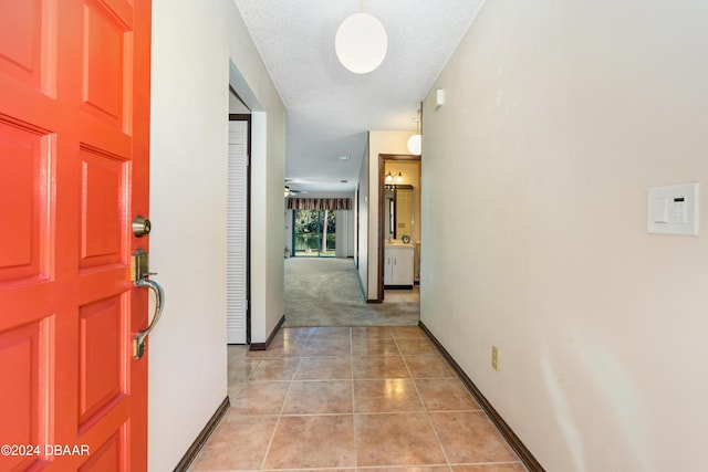 hallway featuring light tile patterned flooring and a textured ceiling