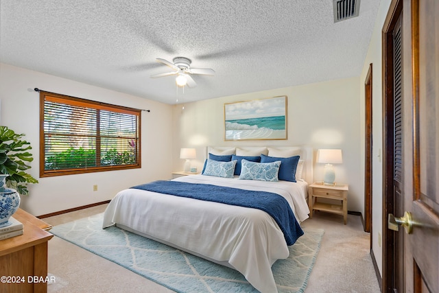 carpeted bedroom featuring ceiling fan and a textured ceiling