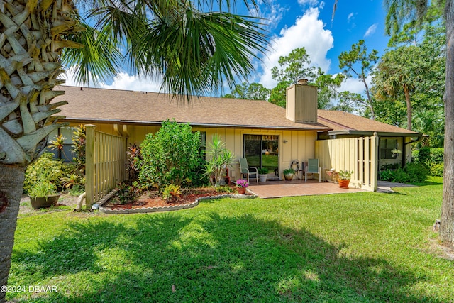 back of house with a patio and a lawn