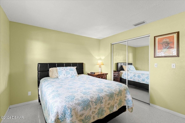 carpeted bedroom with a textured ceiling and a closet