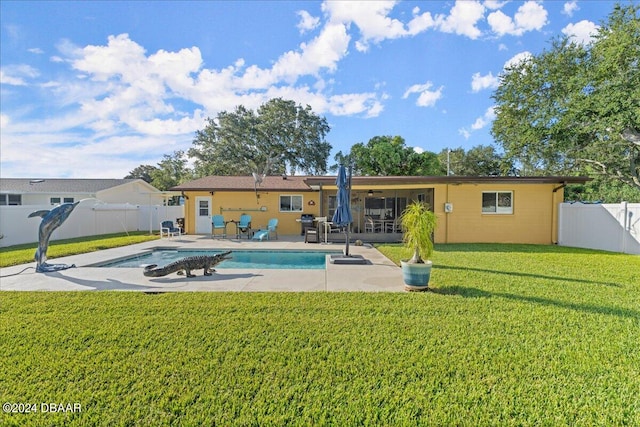 rear view of property featuring a patio, a fenced in pool, and a yard