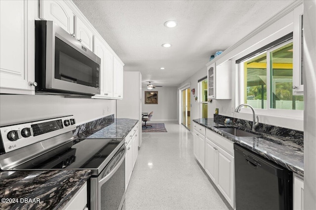 kitchen featuring dark stone counters, white cabinetry, appliances with stainless steel finishes, a textured ceiling, and sink