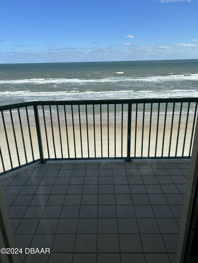 balcony with a water view and a view of the beach