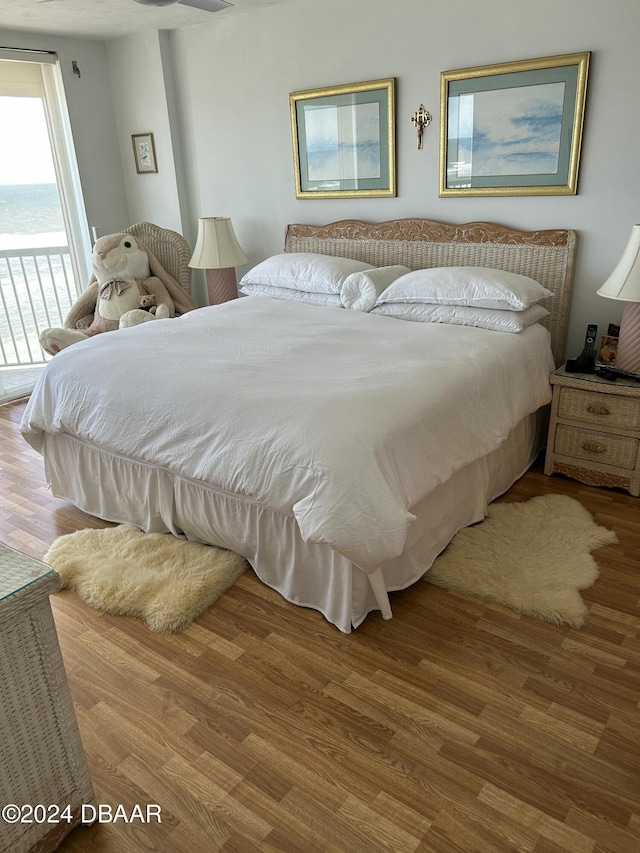 bedroom with hardwood / wood-style floors and a water view