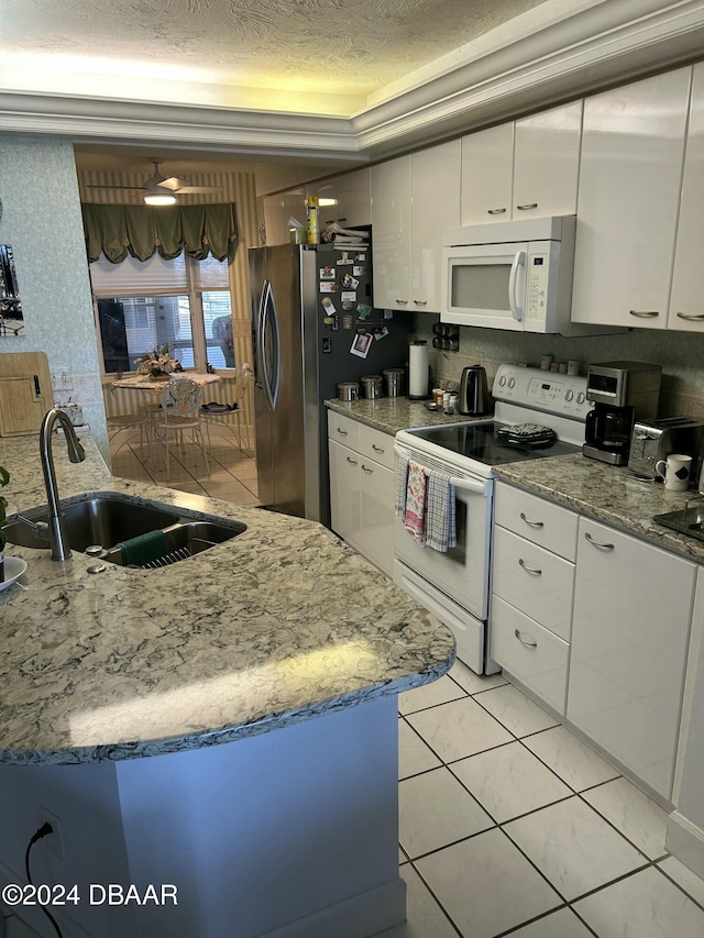 kitchen featuring white appliances, sink, light tile patterned floors, a textured ceiling, and white cabinetry