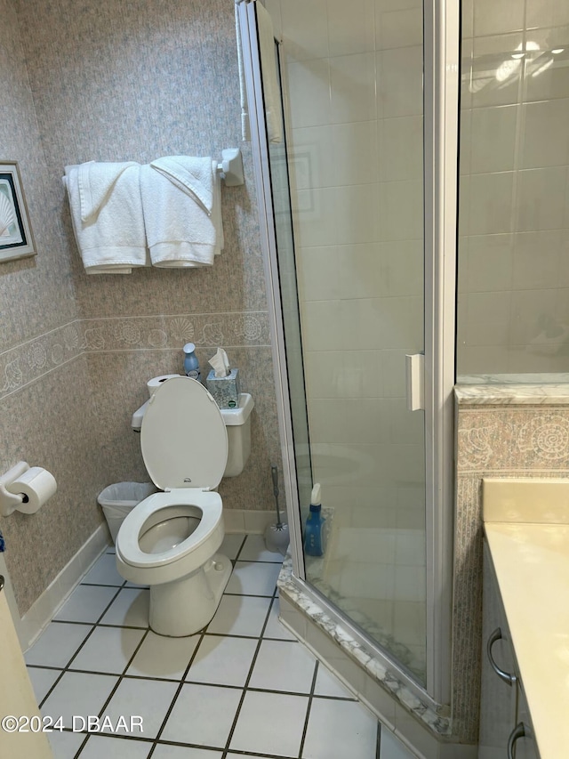 bathroom with tile patterned floors, vanity, a shower with shower door, and toilet