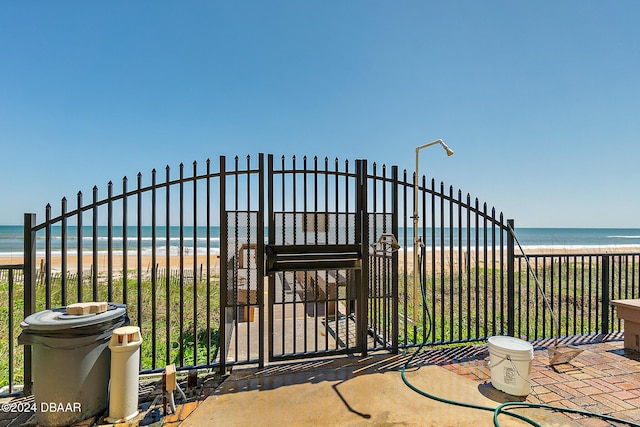 view of gate with a water view and a view of the beach