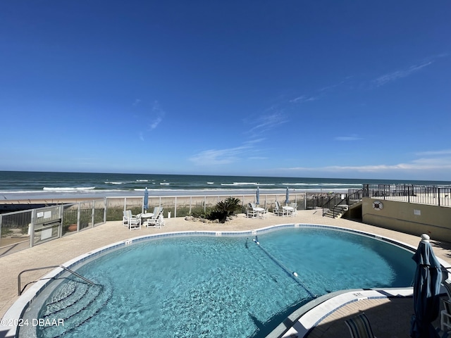 view of swimming pool with a beach view, a patio, and a water view