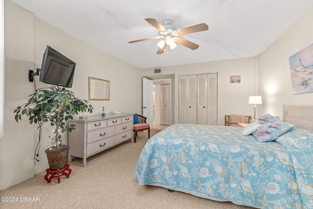 bedroom featuring ceiling fan, a closet, light colored carpet, and a textured ceiling