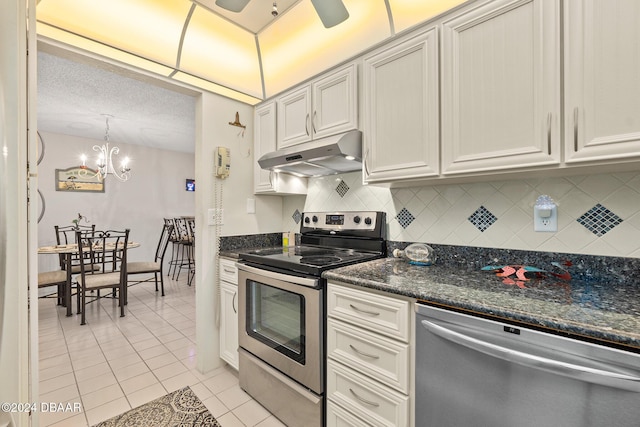 kitchen featuring decorative backsplash, ceiling fan with notable chandelier, stainless steel appliances, hanging light fixtures, and light tile patterned flooring