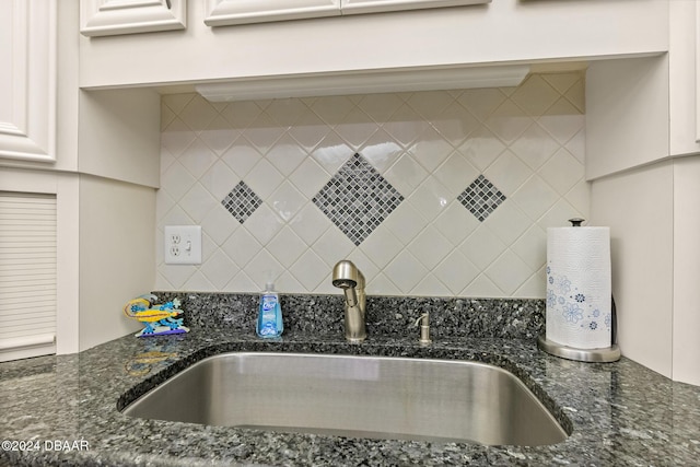 kitchen featuring tasteful backsplash, sink, white cabinets, and dark stone counters