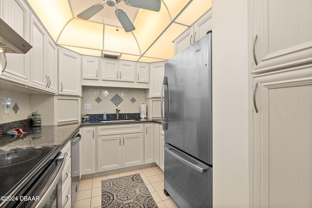 kitchen with sink, stainless steel appliances, dark stone counters, decorative backsplash, and exhaust hood