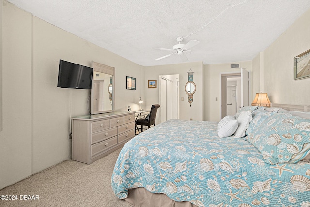 carpeted bedroom with ceiling fan and a textured ceiling