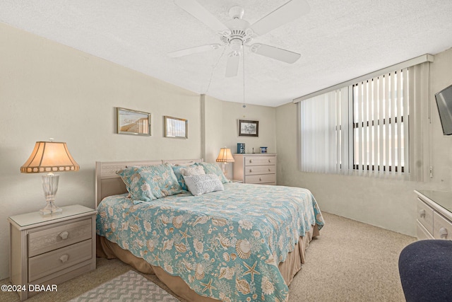 bedroom featuring light carpet, a textured ceiling, and ceiling fan