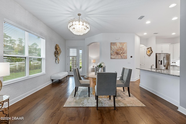 dining space with sink, dark hardwood / wood-style flooring, plenty of natural light, and an inviting chandelier