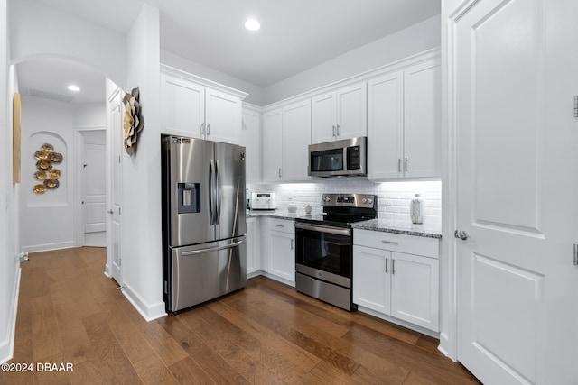 kitchen featuring decorative backsplash, appliances with stainless steel finishes, light stone countertops, white cabinets, and dark hardwood / wood-style floors