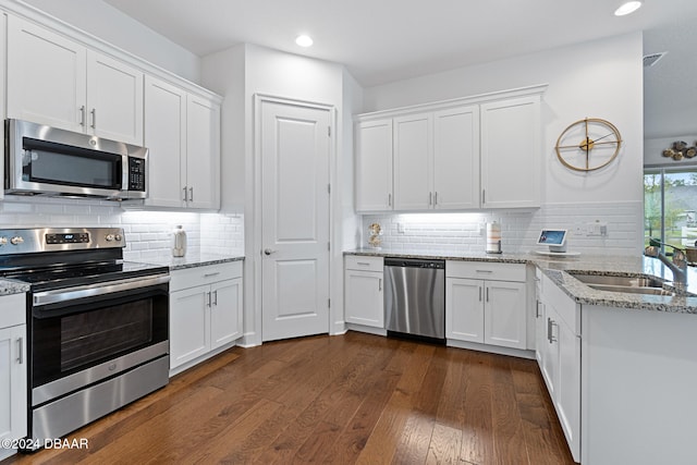 kitchen with decorative backsplash, appliances with stainless steel finishes, sink, white cabinets, and dark hardwood / wood-style floors