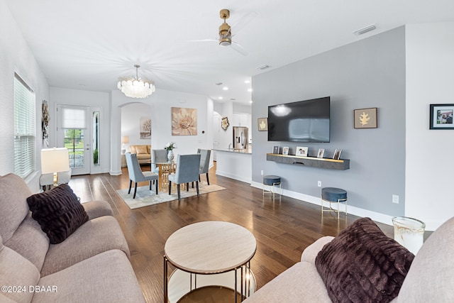 living room with ceiling fan with notable chandelier and dark hardwood / wood-style floors