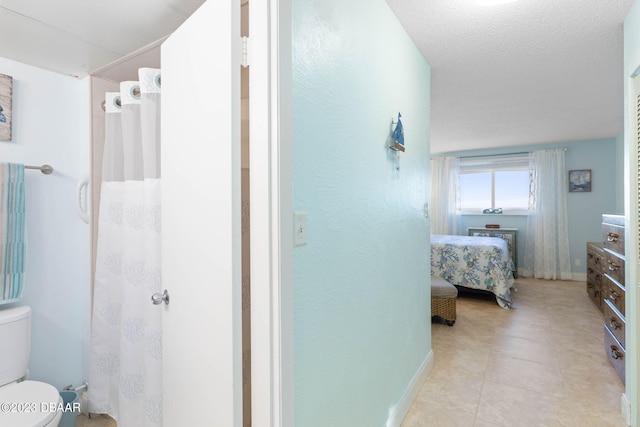 bathroom with a textured ceiling, tile patterned floors, and toilet