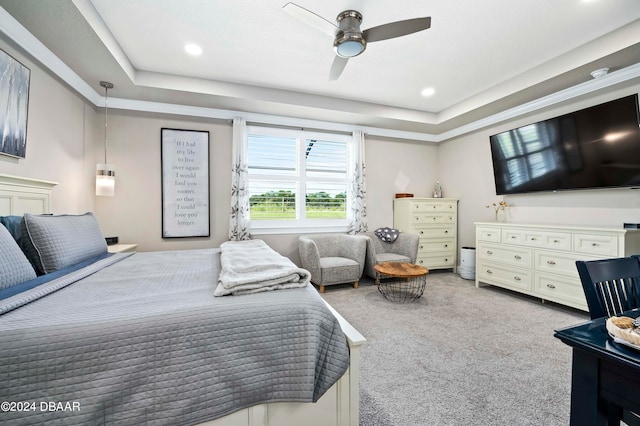 bedroom with ceiling fan, a raised ceiling, and light colored carpet