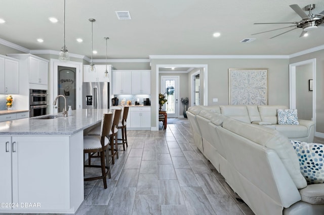 living room featuring crown molding, sink, and ceiling fan