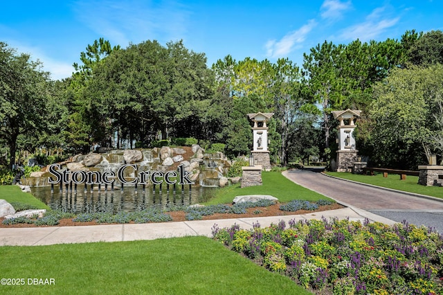 community / neighborhood sign featuring a yard and a water view