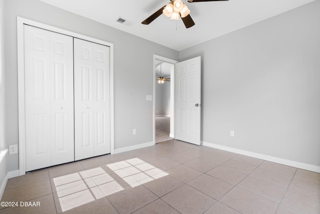 unfurnished bedroom with light tile patterned flooring, ceiling fan, and a closet