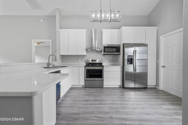 kitchen featuring kitchen peninsula, appliances with stainless steel finishes, wall chimney exhaust hood, and sink