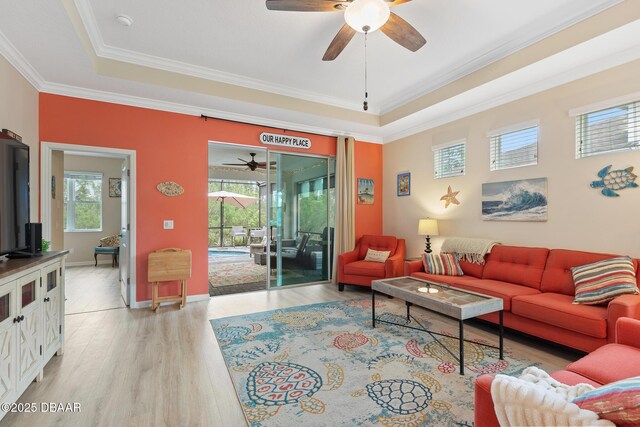 living room featuring ornamental molding, ceiling fan with notable chandelier, and light wood-type flooring