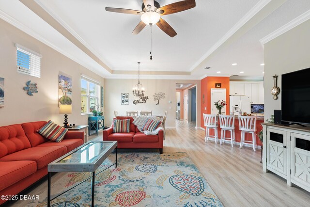 living room featuring light hardwood / wood-style floors, ceiling fan, crown molding, and a tray ceiling